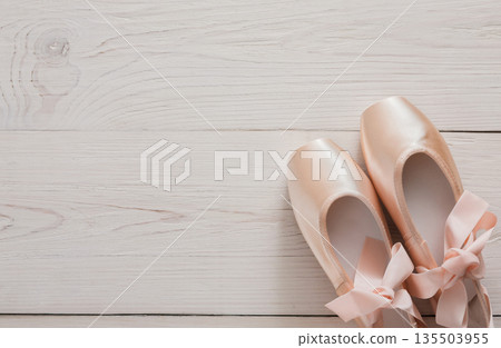 Pastel pink ballet shoes background. New pointe shoes with satin ribbon lay on white rustic shubby chic wood, top view with copy space 135503955