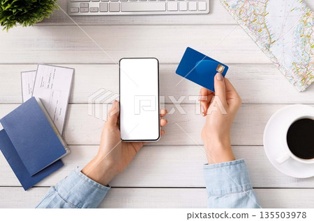 Preparing for travel. Woman using smartphone with blank screen and credit card for booking hotel, mockup 135503978