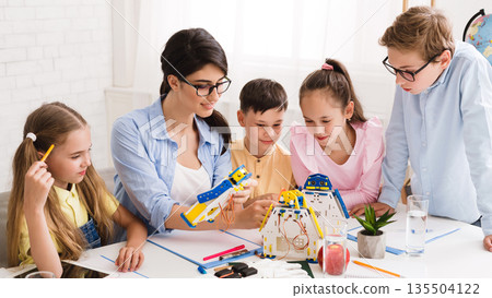 Little technicians working together with teacher in robotics class, creating diy robot 135504122