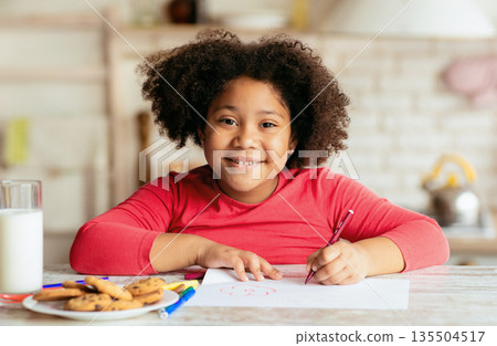 Portrait Of Happy Cute Little Black Girl Drawing In Kitchen, Adorable African American Female Child Sitting At Table With Cookies And Milk And Smiling At Camera, Closeup Shot With Free Space Portrait Of Happy Cute Little Black Girl Drawing In Kitchen, Adorable African American Female Child Sitting At Table With Cookies And Milk And Smiling At Camera, Closeup Shot With Free Space 135504517