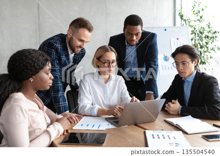 Teamwork. Multicultural Colleagues Sitting At Laptop Working Together On Business Project In Modern Office. Colleagues Unity, Collaboration And Cooperation. Selective Focus 135504540