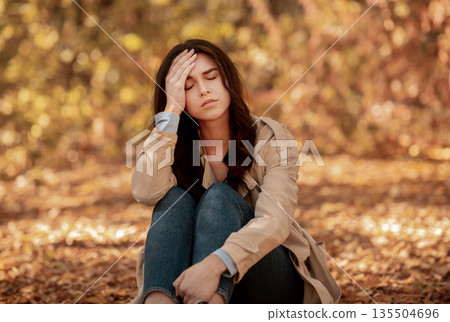 Tired or depressed young woman touching her head at autumn park. Millennial lady suffering from terrible headache, feeling lonely, stressed or unhappy, having problem Tired or depressed young woman touching her head at autumn park. Millennial lady suffering from terrible headache, feeling lonely, stressed or unhappy, having problem 135504696
