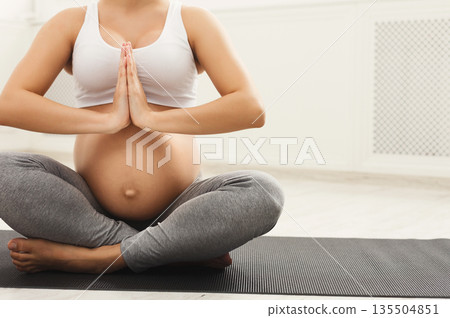 Unrecognizable pregnant woman training yoga in lotus pose. Young happy expectant relaxing, thinking about her baby and enjoying her future life. Motherhood, pregnancy, training, yoga concept Unrecognizable pregnant woman training yoga in lotus pose. Young happy expectant relaxing, thinking about her baby and enjoying her future life. Motherhood, pregnancy, training, yoga concept 135504851
