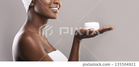 Professional cosmetics for skin concept. Opened cream jar on palm of beautiful african american woman, panorama with free space 135504921