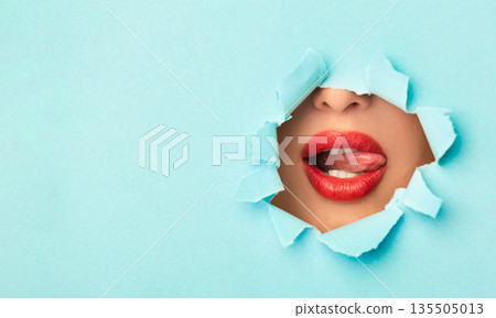 Woman with red lips playing with tongue in turquoise paper hole, free space Woman with red lips playing with tongue in turquoise paper hole, free space 135505013