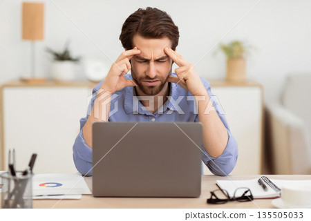 Unhappy Businessman Suffering From Headache Pain Touching And Massaging Aching Head Sitting At Laptop Computer In Modern Office. Health Problem, Painful Migraine Concept. Selective Focus Unhappy Businessman Suffering From Headache Pain Touching And Massaging Aching Head Sitting At Laptop Computer In Modern Office. Health Problem, Painful Migraine Concept. Selective Focus 135505033