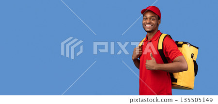 Best Delivery Service Concept. Portrait of confident smiling black male courier wearing red uniform and thermo backpack bag showing thumbs up gesture and looking at camera isolated on blue background Best Delivery Service Concept. Portrait of confident smiling black male courier wearing red uniform and thermo backpack bag showing thumbs up gesture and looking at camera isolated on blue background 135505149