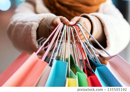 Discount, Sale And Consumerism Concept. Closeup of smiling african american woman holding many shopping bags and showing it to camera. Excited black female shopaholic carrying purchases Discount, Sale And Consumerism Concept. Closeup of smiling african american woman holding many shopping bags and showing it to camera. Excited black female shopaholic carrying purchases 135505192