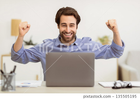 Joyful Businessman At Laptop Shaking Fists And Shouting Celebrating Business Success Looking At Computer Screen Sitting At Desk In Modern Office. Victory Celebration, Successful Career, Great News 135505195