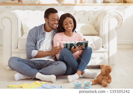Preparing for childbirth concept. Pregnant black couple making checklist of baby things before going to maternity hospital. Loving husband taking notes of child stuff for birthing center Preparing for childbirth concept. Pregnant black couple making checklist of baby things before going to maternity hospital. Loving husband taking notes of child stuff for birthing center 135505242