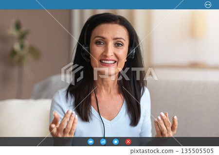 Video Conference. Portrait Of Senior Lady Wearing Headset Having Virtual Chat, Looking And Talking To Camera During Web Call, Explaining And Discussing Something In Headphones. Teleworking 135505505
