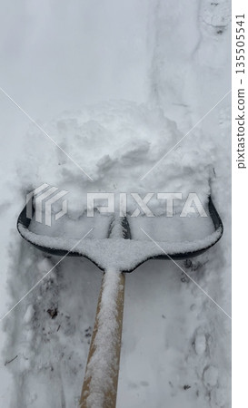 Close-up of shovel shoveling snow off the path Close-up of shovel shoveling snow off the path 135505541