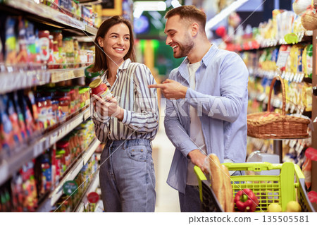 Grocery Shopping. Young Smiling Family Couple Buying Groceries In Supermarket Store Indoors. Two Buyers Standing With Shopping Trolley Cart In Aisles Choosing Food Products And Laughing Grocery Shopping. Young Smiling Family Couple Buying Groceries In Supermarket Store Indoors. Two Buyers Standing With Shopping Trolley Cart In Aisles Choosing Food Products And Laughing 135505581