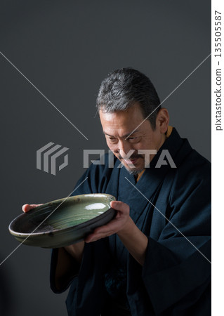 Male potter holding a plate Male potter holding a plate 135505587