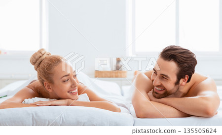 Relaxed Spouses At Spa Lying On Beds Relaxing And Smiling Each Other, Resting After Massage Therapy Indoor. Beauty Treatment, Body Relaxation And Rejuvenation. Panorama Relaxed Spouses At Spa Lying On Beds Relaxing And Smiling Each Other, Resting After Massage Therapy Indoor. Beauty Treatment, Body Relaxation And Rejuvenation. Panorama 135505624