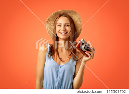 Smiling female photographer posing with camera over yellow studio background Smiling female photographer posing with camera over yellow studio background 135505702