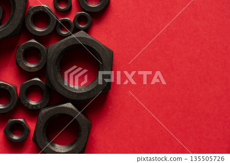 Hexagonal bolt and nut on a red background Hexagonal bolt and nut on a red background 135505726