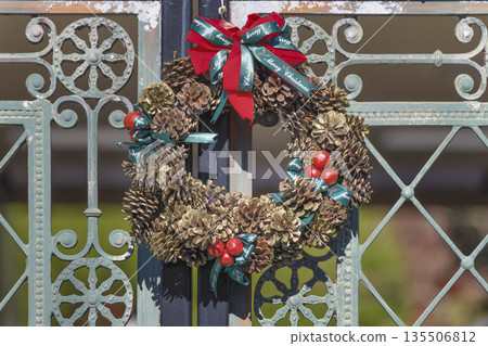 一扇古老的鐵門上裝飾著一個松果聖誕花圈。 135506812