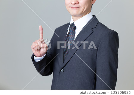 A middle-aged male businessman in a suit pointing his index finger A middle-aged male businessman in a suit pointing his index finger 135506925
