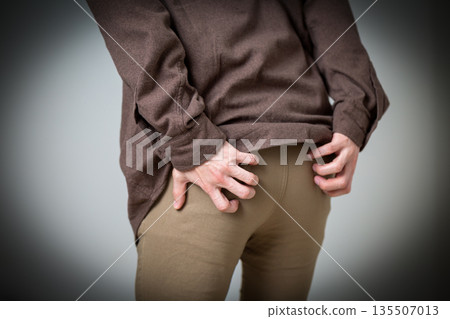 Middle-aged man suffering from itchy buttocks 135507013