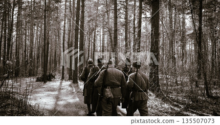 Squad Men Dressed As World War II Russian Soviet Red Army Soldiers Marching Through Spring Forest In Sunny day. Soldier Of WWII WW2 Times. Squad Men Dressed As World War II Russian Soviet Red Army Soldiers Marching Through Spring Forest In Sunny day. Soldier Of WWII WW2 Times. 135507073