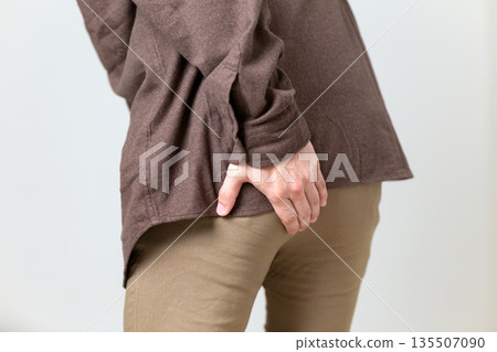 中年男子摀著臀部,痛苦不堪 中年男子摀著臀部,痛苦不堪 135507090