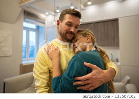 Relaxed happy family couple enjoying hugging each other and demonstrating love in relationships. Relaxed happy family couple enjoying hugging each other and demonstrating love in relationships. 135507102