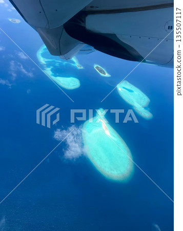 A plane is flying over the ocean and the water is blue 135507117