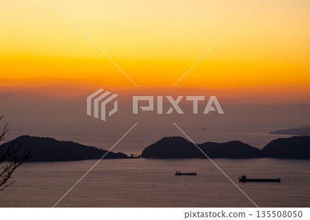 Island silhouettes and sailing ships floating in the orange sky Island silhouettes and sailing ships floating in the orange sky 135508050