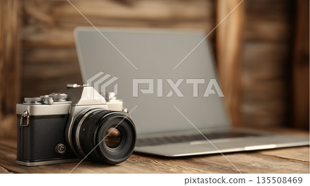 Vintage camera placed beside modern laptop on wooden table showcasing creative workspace 135508469