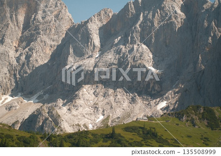 Majestic mountain range with rocky peaks and lush green valley under clear blue sky Majestic mountain range with rocky peaks and lush green valley under clear blue sky 135508999