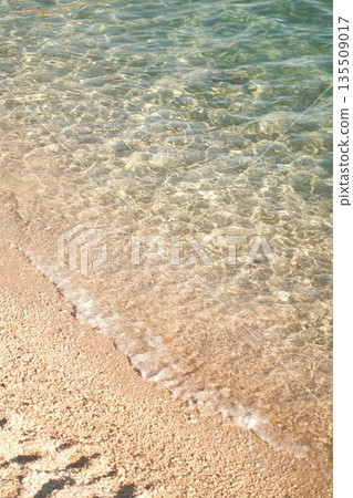 Clear turquoise water gently lapping against sandy beach creating a serene coastal atmosphere Clear turquoise water gently lapping against sandy beach creating a serene coastal atmosphere 135509017
