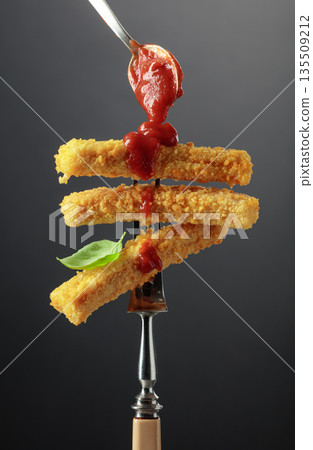 Fish fingers with basil and ketchup on a fork. Fish fingers with basil and ketchup on a fork. 135509212