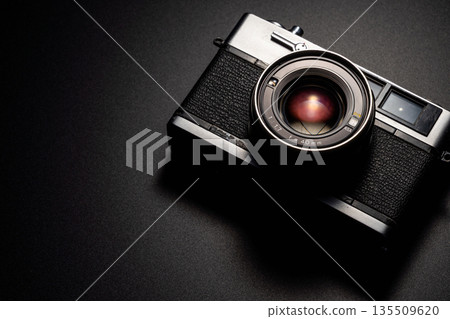 Old film camera in spotlight against a dark background Old film camera in spotlight against a dark background 135509620