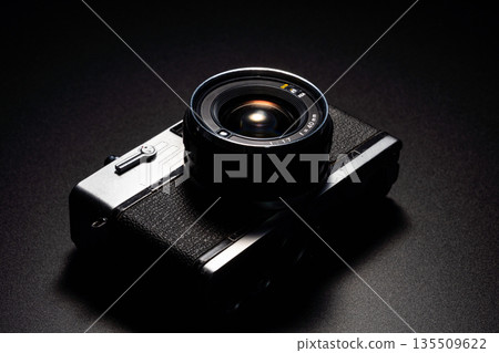 Old film camera in spotlight against a dark background Old film camera in spotlight against a dark background 135509622