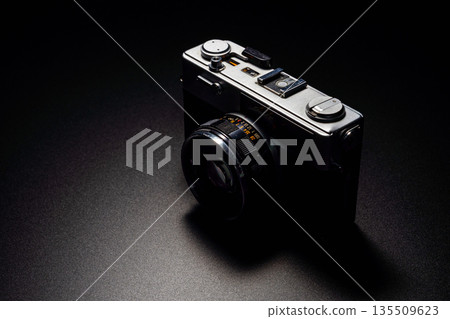 Old film camera in spotlight against a dark background 135509623