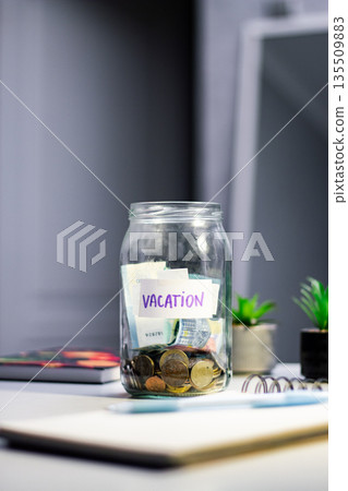 Travel savings in jar. Money being added to travel themed savings container. Inspires adventure planning and purposeful financial habits Travel savings in jar. Money being added to travel themed savings container. Inspires adventure planning and purposeful financial habits 135509883