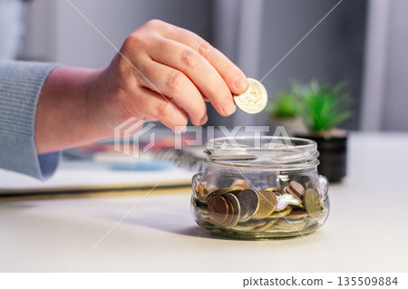 Future planning with long term savings jar. Hand adding substantial savings to future security container. Financial planning and safety concepts 135509884