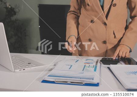 Close-up of businessman's hands making notes, mobiles, chart, desk, office Close-up of businessman's hands making notes, mobiles, chart, desk, office 135510074