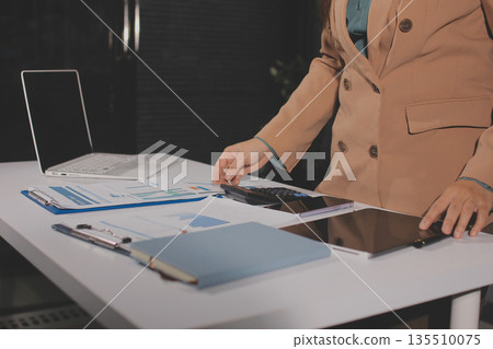 Close-up of businessman's hands making notes, mobiles, chart, desk, office Close-up of businessman's hands making notes, mobiles, chart, desk, office 135510075