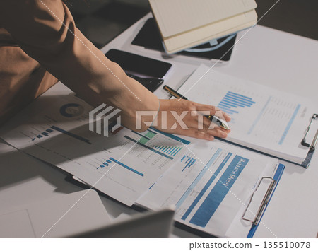 Close-up of businessman's hands making notes, mobiles, chart, desk, office 135510078