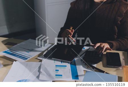 Close-up of businessman's hands making notes, mobiles, chart, desk, office Close-up of businessman's hands making notes, mobiles, chart, desk, office 135510119