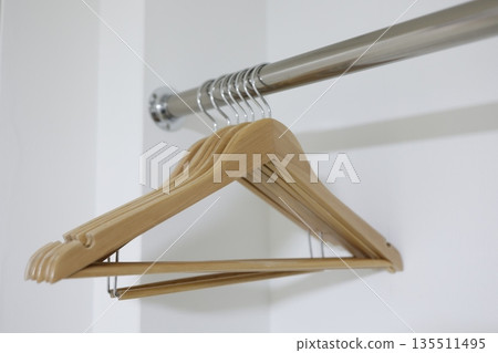 一個空蕩蕩的白色衣櫥，裡面擺放著多個木製衣架。 135511495