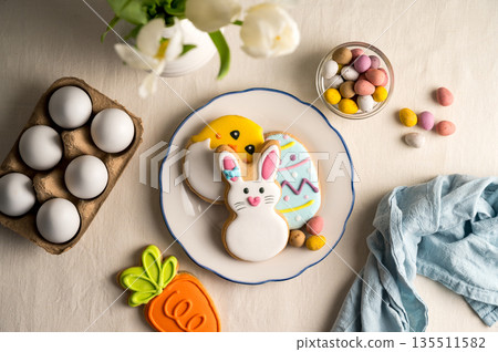 Easter festive background. Colourful easter cookies bunny, egg, chick and carrot. White spring tulips bouquet. Easter festive background. Colourful easter cookies bunny, egg, chick and carrot. White spring tulips bouquet. 135511582