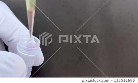 Actual image of medical, testing, and experiment work in which a person wearing white gloves operates a micropipette and dispenses reagents into a microtube Actual image of medical, testing, and experiment work in which a person wearing white gloves operates a micropipette and dispenses reagents into a microtube 135511699