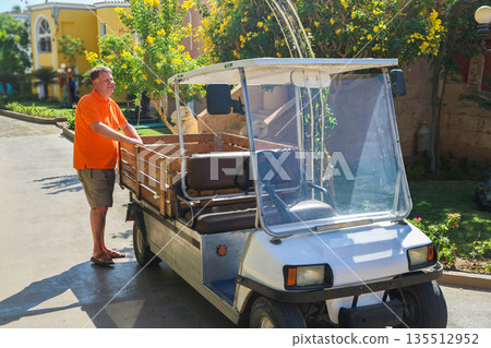 A man loads things into the back of a small electric car near his home A man loads things into the back of a small electric car near his home 135512952