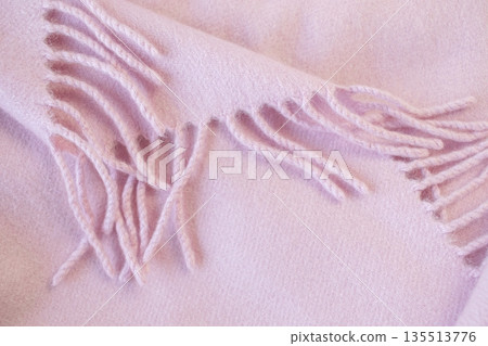 Pale pink cashmere scarf with fringe around the edge. Soft pink draped fabric texture. 135513776