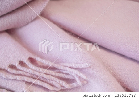 Pale pink cashmere scarf with fringe around the edge. Soft pink draped fabric texture. 135513788