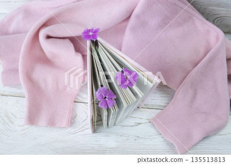 Pink notebook with flowers on a pink cozy sweater, soft pink composition with a book, flowers and cozy cashmere textiles Pink notebook with flowers on a pink cozy sweater, soft pink composition with a book, flowers and cozy cashmere textiles 135513813