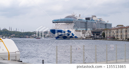 A large cruise ship is anchored in Bosphorus, offering stunning views of Istanbuls skyline featuring historic landmarks on a cloudy day. 135513865